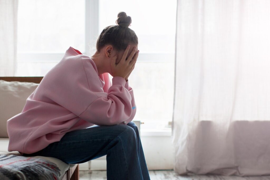 Unhappy depressed crying teenage girl sit on couch at home