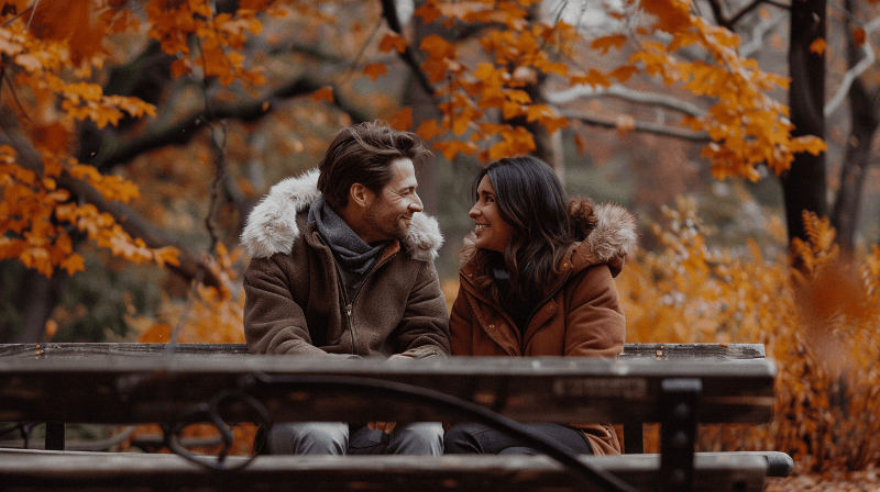 emotional attraction displayed between a man and woman sitting outside on a park bench during autumn-800x
